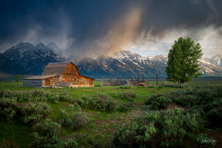 John Mounton barn in Wyomings Mormon Row at sunet with the Teton mountain range.