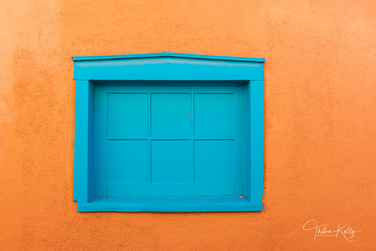 Typical of the architecture in New Mexico, the simple yet vibrant colors of structures are dazzling, the blue window is striking...